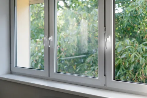 Open window overlooking lush green trees and foliage outside.