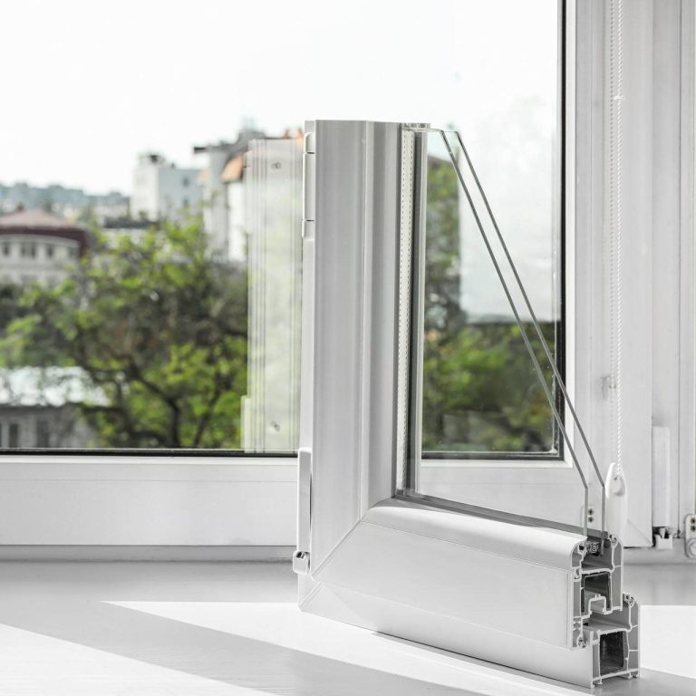 White window frame with a view of greenery and buildings outside.